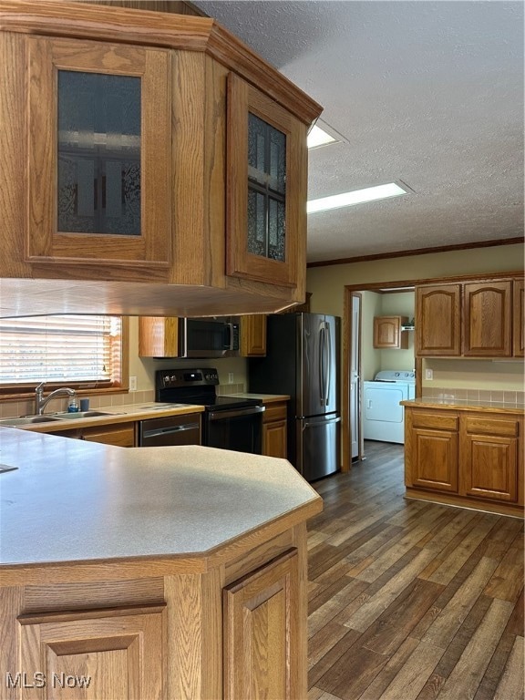 Kitchen with crown molding, stainless steel range oven, brown cabinets, washer / dryer, and Luxury Vinyl Floors