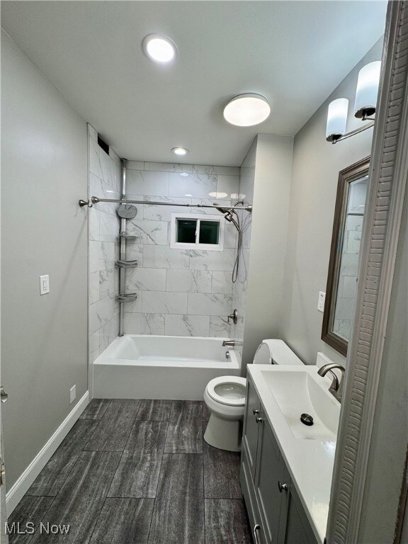 Full bathroom featuring tiled shower / bath combo, vanity, and toilet