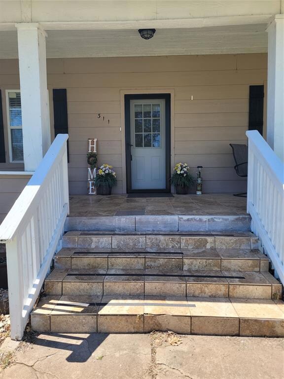 Doorway to property featuring covered porch
