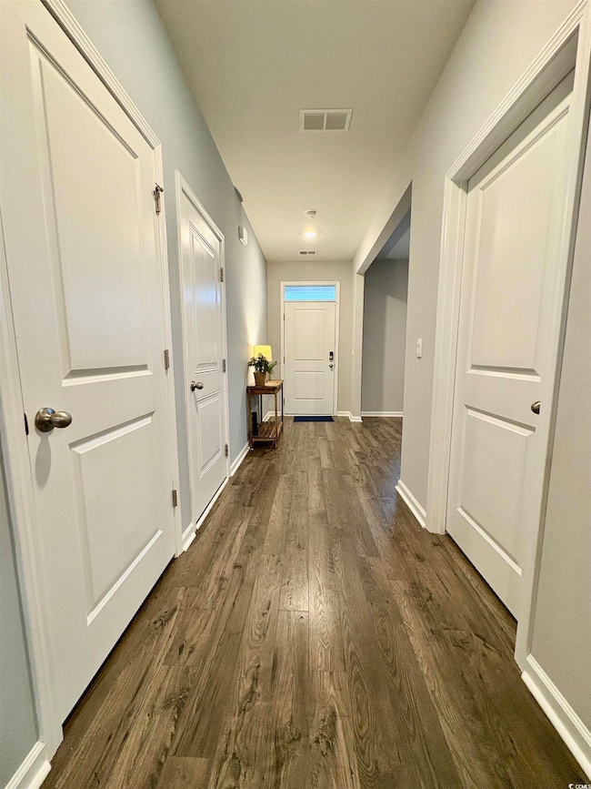 Corridor featuring dark wood-style floors and baseboards