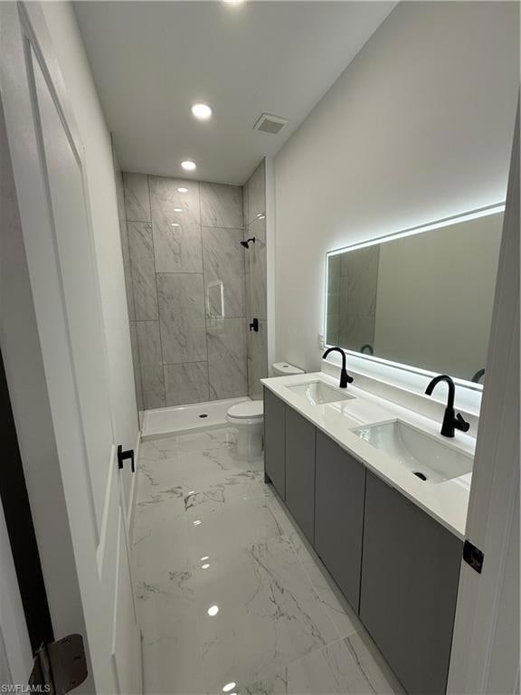 Bathroom featuring marble finish floors, recessed lighting, double vanity, and a tile shower