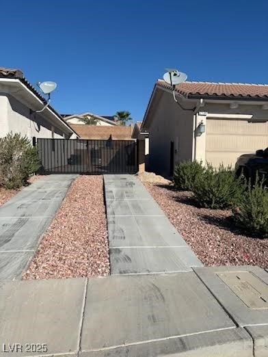 View of side of property with a tiled roof, stucco siding, and a gate