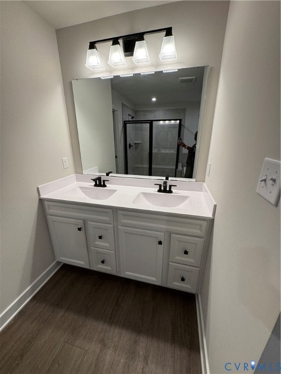 Full bathroom featuring double vanity, dark wood-type flooring, and a stall shower