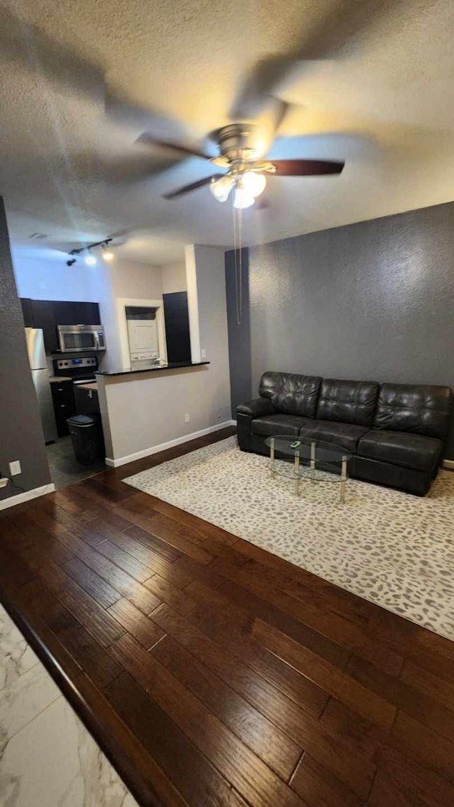 View from front door into the Living area featuring a wood flooring, and ceiling fan with open kitchen plan