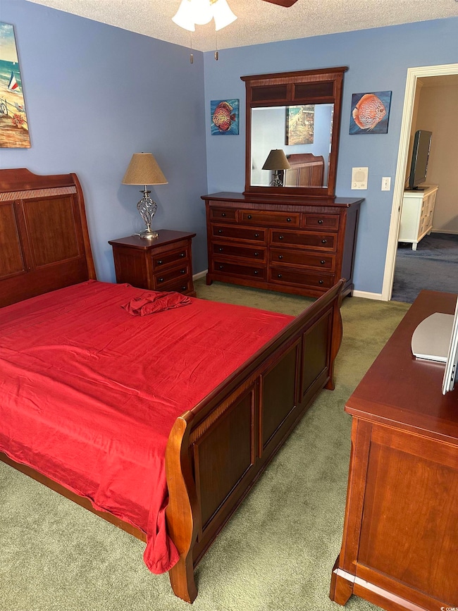 Bedroom with carpet flooring, baseboards, ceiling fan, and a textured ceiling