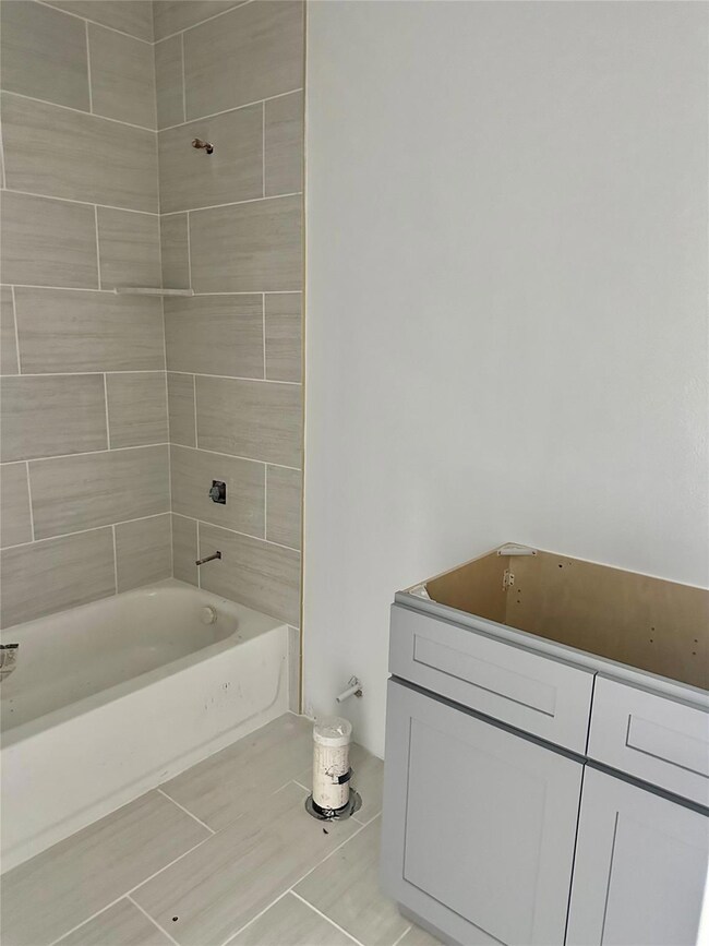 Bathroom with tiled shower / bath combo, vanity, a