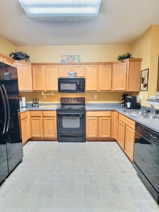Kitchen featuring black appliances, sink, light ti