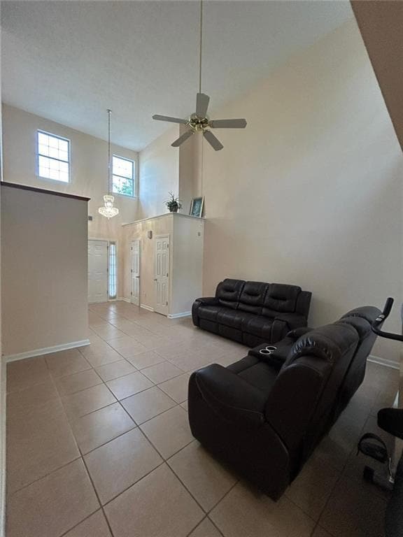 Living area featuring a high ceiling, light tile patterned flooring, a chandelier, and a ceiling fan