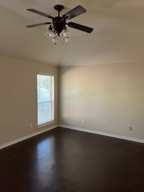 Empty room featuring lofted ceiling, a ceiling fan, and concrete flooring