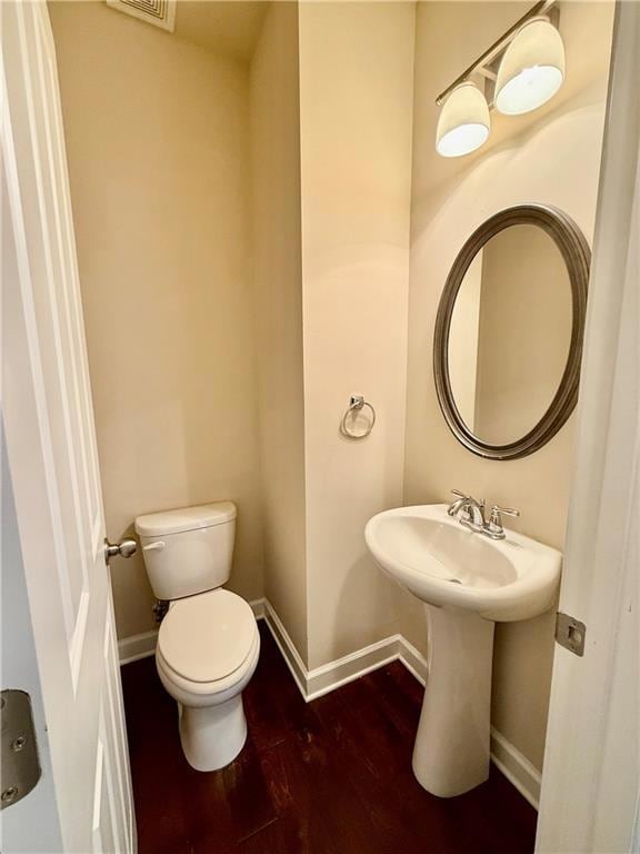 Bathroom with toilet, visible vents, wood finished