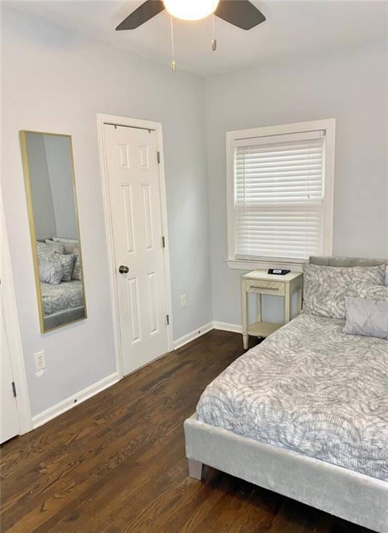 Laundry room featuring stacked washer / drying machine, dark wood-type flooring, and baseboards