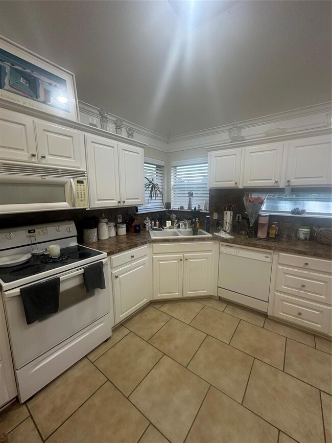 Kitchen featuring crown molding, white cabinets, d