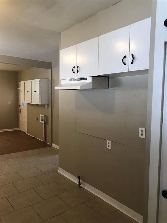 Laundry area with dark wood-type flooring, cabinet