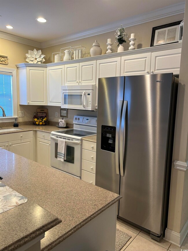 Kitchen featuring ornamental molding, white applia