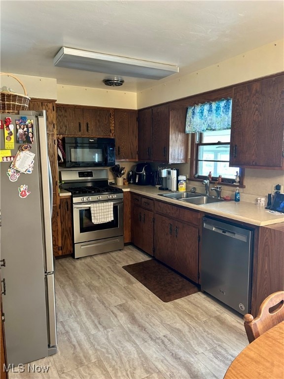 Kitchen featuring dark brown cabinets, stainless steel appliances, light countertops, and light wood finished floors