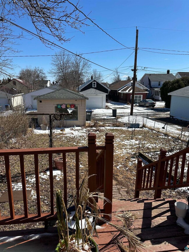 Yard covered in snow with an outdoor structure, a garage, and fence