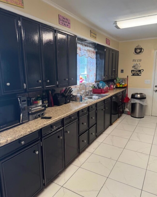 Kitchen with black appliances, sink, cabinetry, an