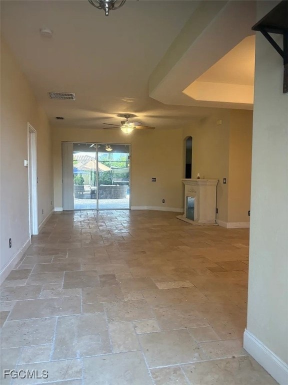 Unfurnished living room with a ceiling fan and stone tile floors