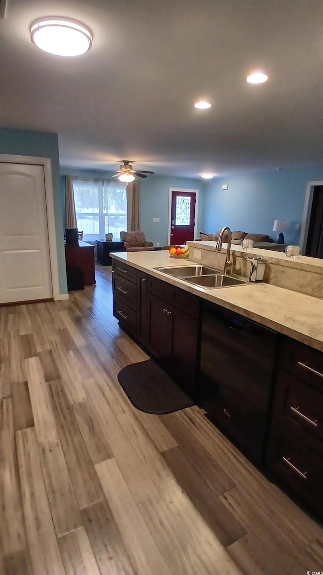 Kitchen featuring dark brown cabinets, light countertops, light wood-type flooring, dishwasher, and recessed lighting