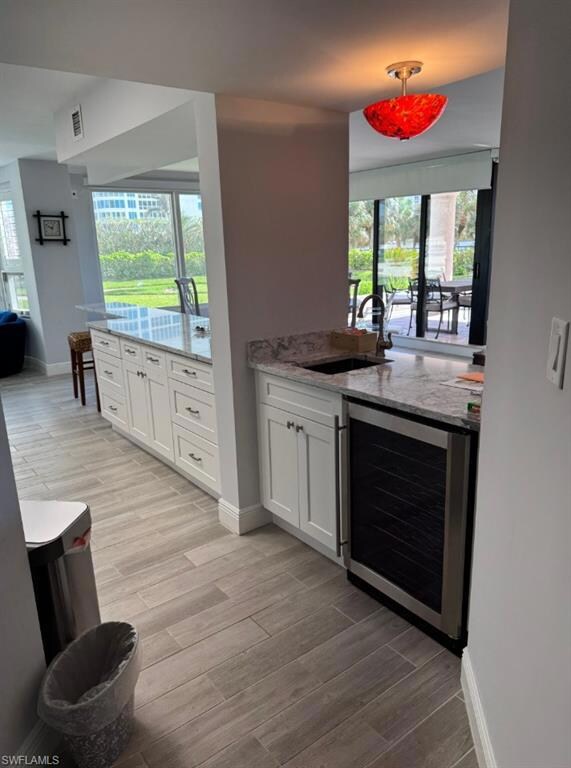 Kitchen with a sink, wine cooler, white cabinets, 