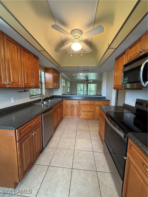 Kitchen featuring stove, dishwasher, a tray ceiling, ceiling fan, and brown cabinetry