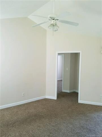 Living room with vaulted ceiling and fan. Doorway 