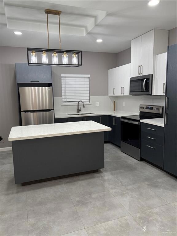 Kitchen featuring stove, fridge, a sink, a center island, and white cabinets