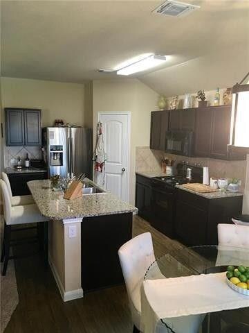 Kitchen featuring black appliances, dark wood-sty