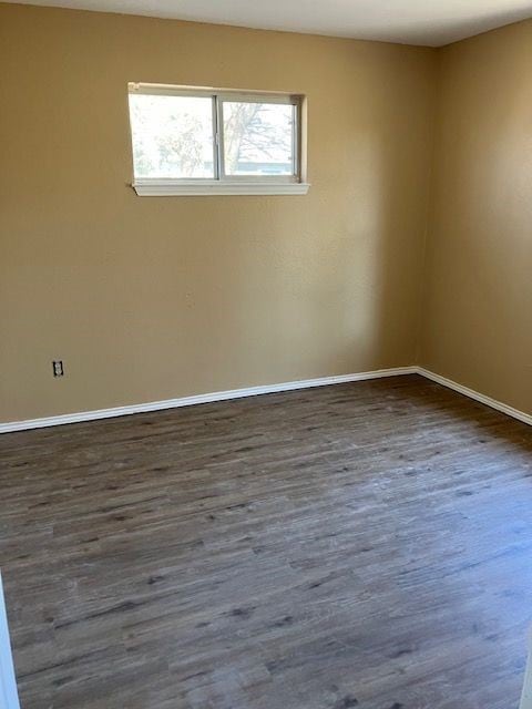 Unfurnished room with dark wood-style flooring and baseboards