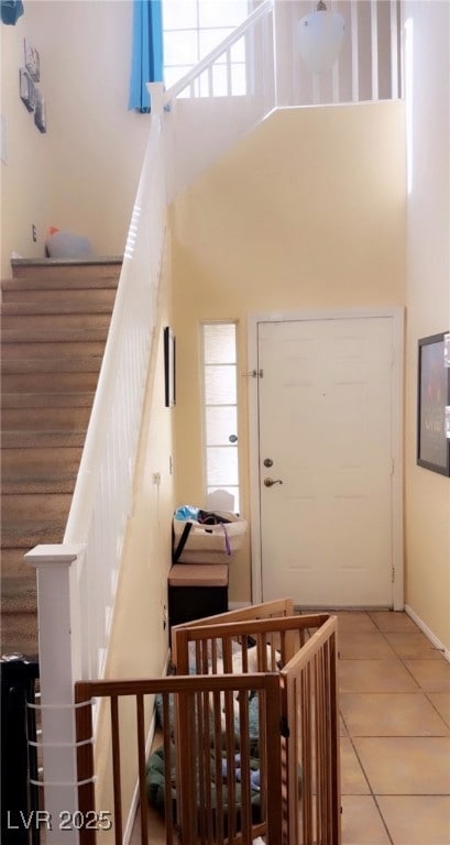 Staircase featuring a high ceiling, tile patterned