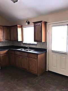 Kitchen featuring range, lofted ceiling, dark countertops, tasteful backsplash, and brown cabinets