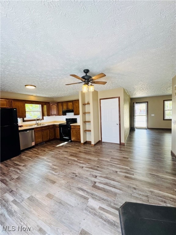 Kitchen with light countertops, black appliances, light wood-style flooring, a textured ceiling, and a ceiling fan