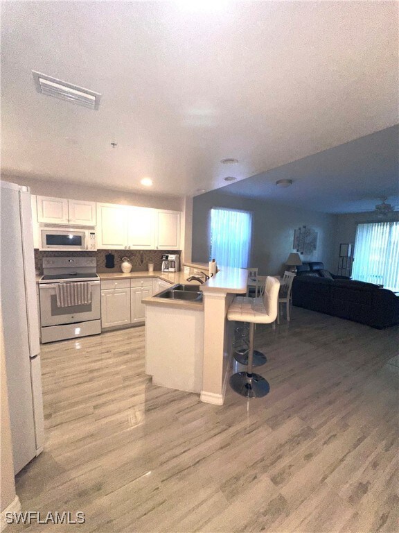 Kitchen with white appliances, white cabinets, a k