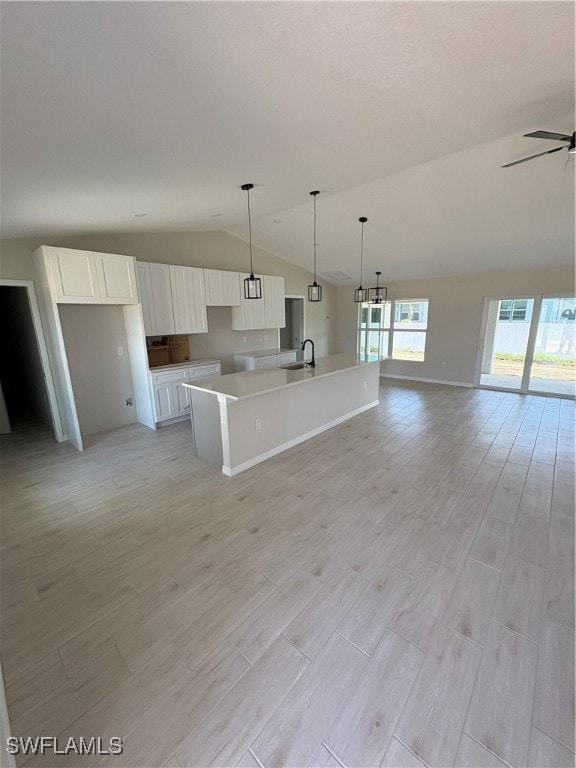 Kitchen featuring vaulted ceiling, white cabinets,