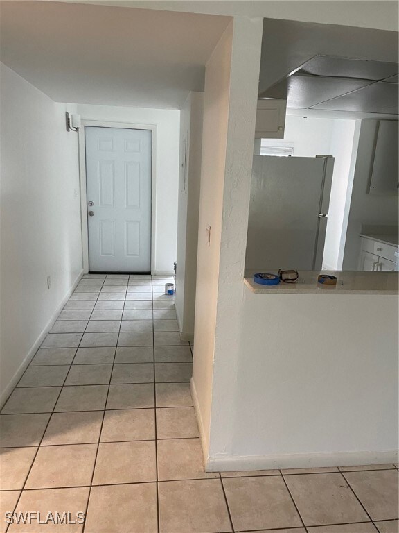 Hall with baseboards and light tile patterned floo