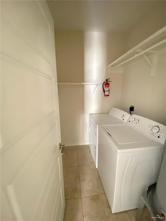 Washroom with electric dryer hookup, washer and clothes dryer, and light tile floors