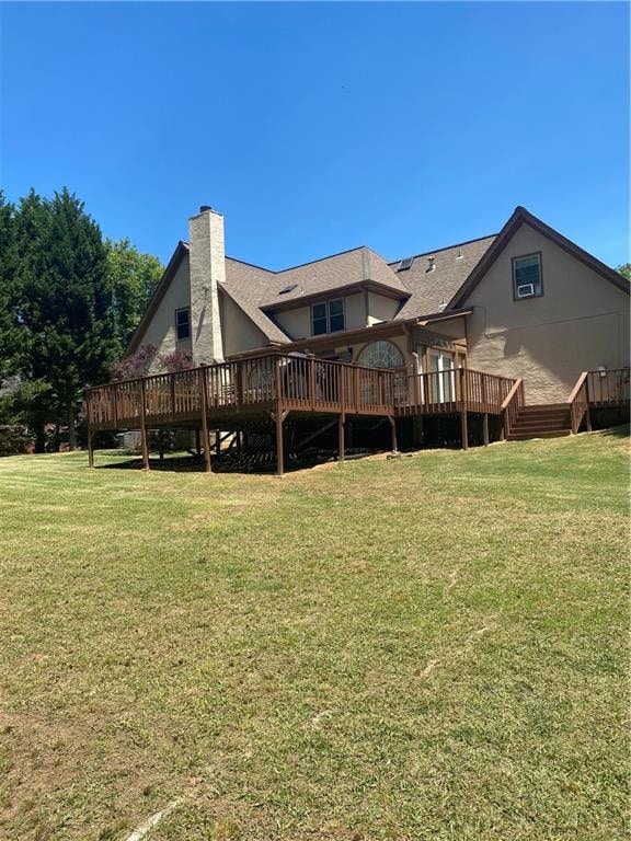 Rear view of property with a chimney, a wooden deck, and a yard