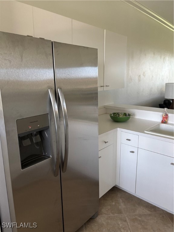 Kitchen with white cabinetry, stainless steel fridge, and light countertops