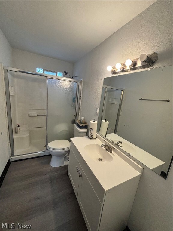 Bathroom featuring vanity, toilet, walk in shower, and hardwood / wood-style flooring