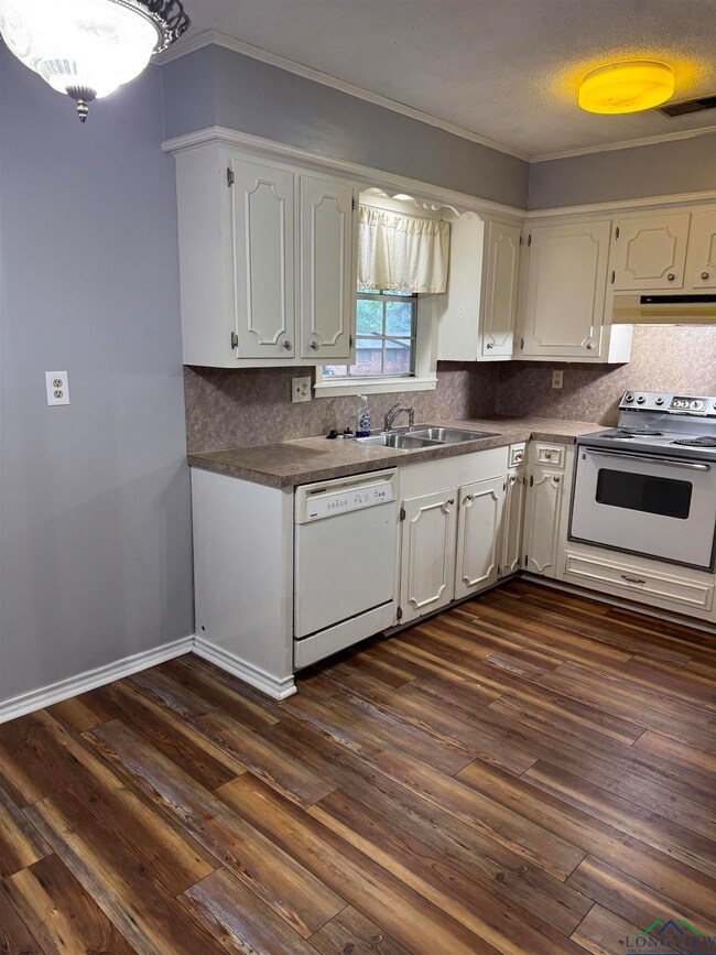 Kitchen featuring dishwasher, electric range oven, white cabinetry, dark wood finished floors, and crown molding