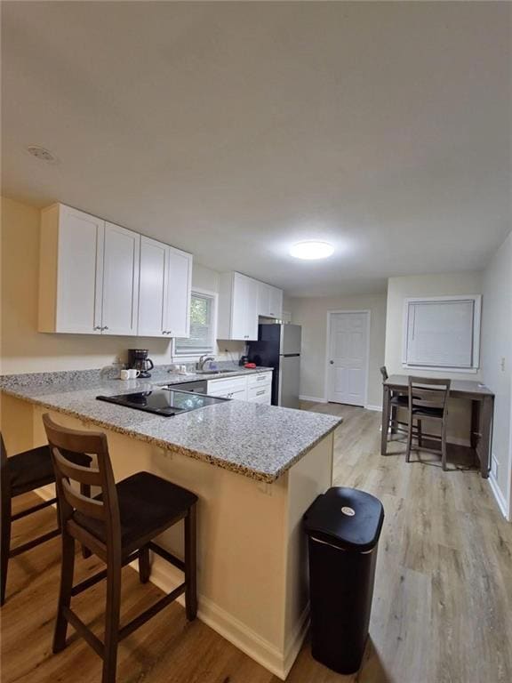 Kitchen with light stone counters, a peninsula, wh