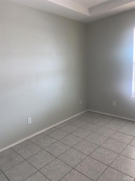 Empty room featuring baseboards and light tile patterned flooring