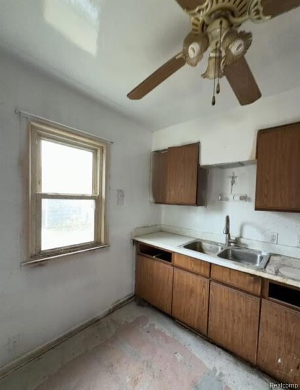 Kitchen with brown cabinetry, light countertops, and ceiling fan