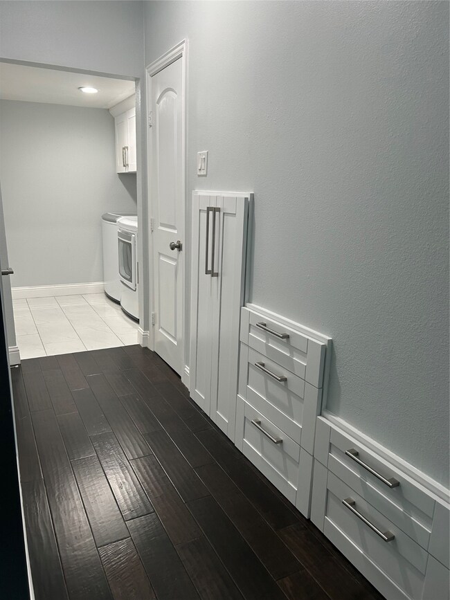 Hallway features plenty of built-in wall drawers leading to the washer and dryer room.