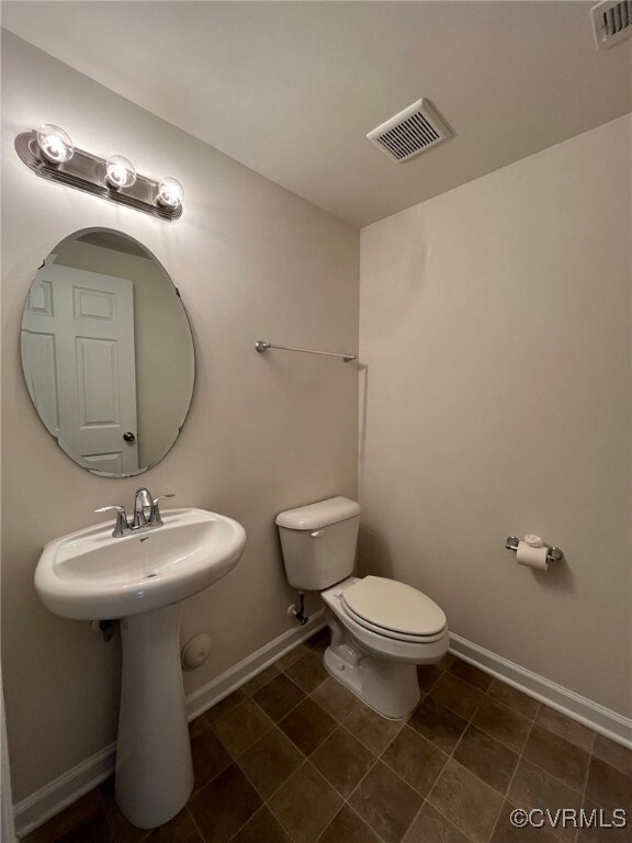 Half bathroom featuring toilet, baseboards, and a
