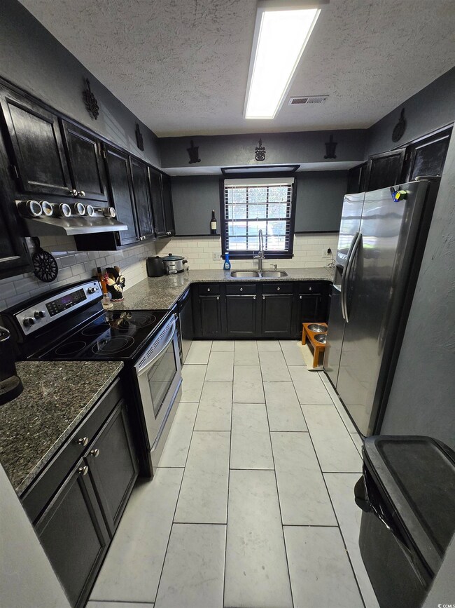 Kitchen with a textured ceiling, a sink, stainless