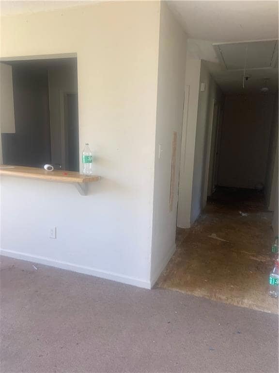 Hallway featuring attic access and baseboards