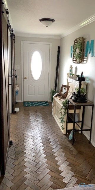Front entry with parquet flooring and coat closet.