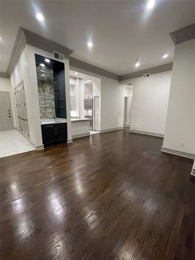 Unfurnished living room featuring crown molding, dark wood-style flooring, and recessed lighting