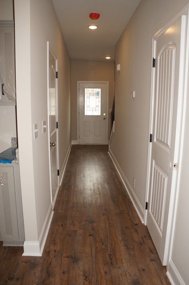 From the Kitchen looking down the Hallway towards the Front Door.  Half Bathroom on the right and entrance to the Garage on the Left in the hall.